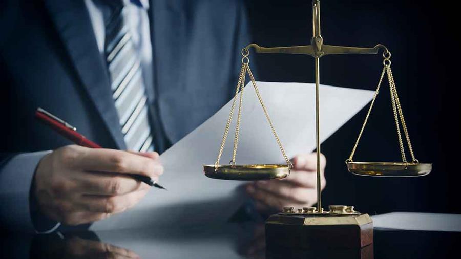 man in a suit examining a piece of paper in front of legal scales